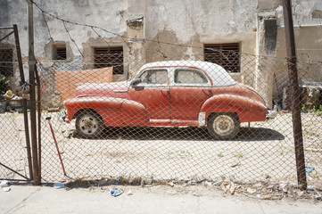 Vintage American car stands parked in the sun on a dusty lot in Centro, Havana, Cuba