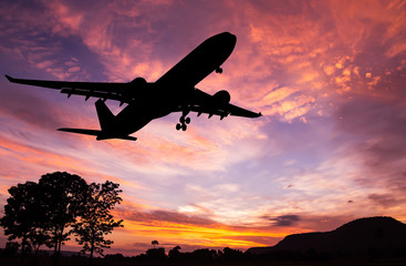 Silhouetted commercial airplane flying at sunset