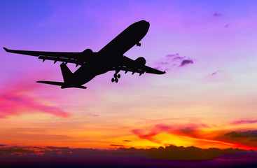 Fototapeta na wymiar Silhouetted commercial airplane flying at sunset