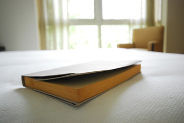 Book on a bed next to a large window