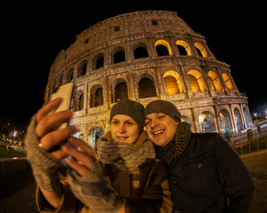 Happy couple making selfie by Coliseum at night