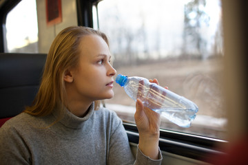 Woman drinking water and looking out train window