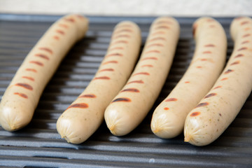 Sausages roasting on electric grill.