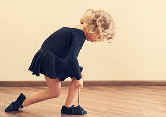 Funny little girl put on shoes for dance.
