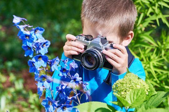 Little boy with retro SLR camera shooting macro flowers