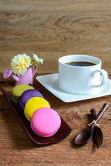 Obraz na płótnie Canvas Colorful macaroons and a cup of coffee with notebook on wooden t