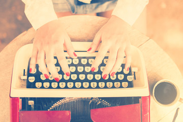 Girl at the table typing on a typewriter, vintage photo effect