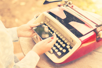 girl with cell phone and typewriter, vintage photo effect