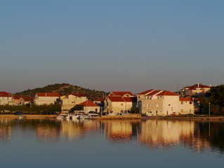 Fototapeta na wymiar Houses with red roofs at the bay of the village Betina on the island Murter in the Adriatic sea of Croatia