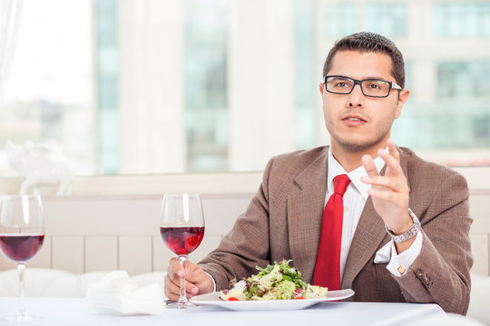 Attractive young man with suit is eating in restaurant
