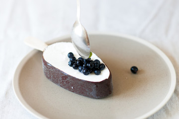  Ice cream with chocolate glaze on plate garnished with fresh blueberries.