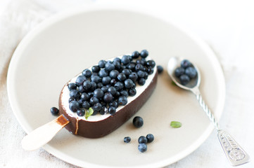  Ice cream with chocolate glaze on plate garnished with fresh blueberries.