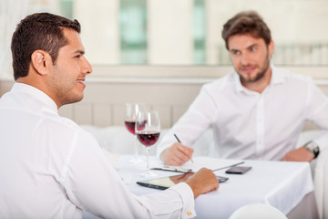 Successful young men has a business lunch in restaurant
