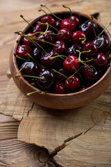 Wooden bowl with sweet organic cherries, close-up, studio shot