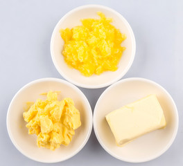 A block of butter, margarine and ghee in white bowls 