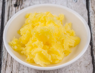 A bowl of Indian ghee in white bowl over wooden background