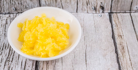 A bowl of Indian ghee in white bowl over wooden background