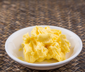 A bowl of margarine in white bowl over wicker background