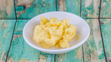 A bowl of margarine in white bowl over wooden background