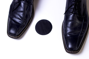 Standpunkt,Herrenschuhe stehen auf schwarzem Punkt