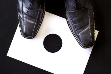 Standpunkt,Herrenschuhe stehen auf schwarzem Punkt