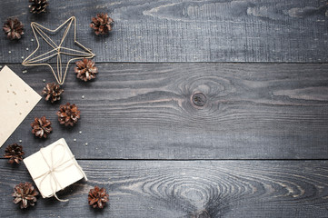 Gift, card, pine cones and cinnamonin on the dark wooden texture