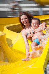 child and mom playing with the slide in the pool