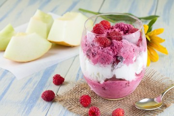 Glass cup full of fruit ice cream and raspberries around