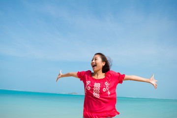 沖縄のビーチをバックにはしゃぐ女性(1)