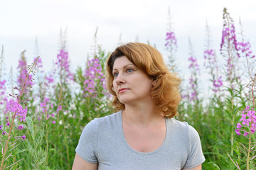 Portrait of  woman near willow-herb in the field