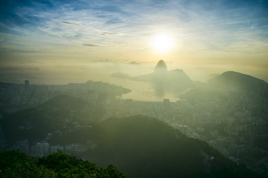 Scenic sunrise in Rio de Janeiro Brazil glows golden over Guanabara Bay with a skyline silhouette of Sugarloaf Mountain