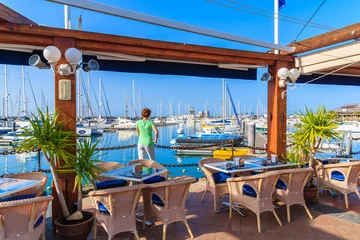 Rolgordijnen Young woman tourist standing in restaurant in Rubicon yacht port, Lanzarote, Canary Islands, Spain © pkazmierczak
