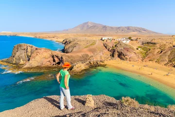 Tischdecke Young woman tourist standing on cliff looking at Papagayo beach, Lanzarote, Canary Islands, Spain © pkazmierczak