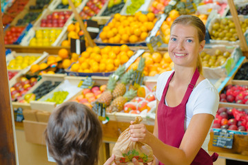 Shop assistant serving customer in grocers