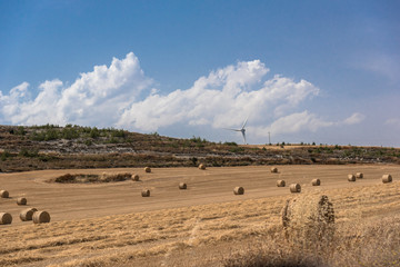 Landscape of straw bales with wind turbine in background