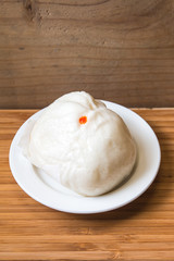 Steamed dumpling on white dish with wood background
