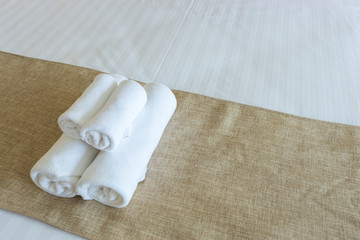 Close up of nice towels on white bed sheet with yellow ribbon