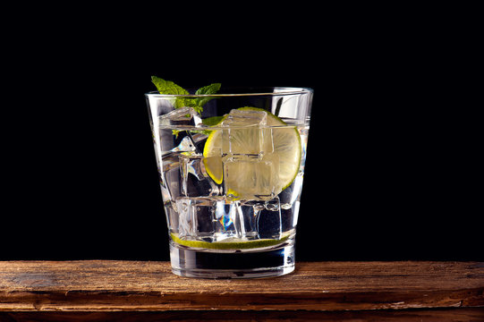 alcoholic drink with lemon and ice on a old wooden table