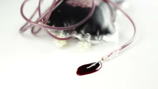 A leaking blood donation bag, needle and drops of blood