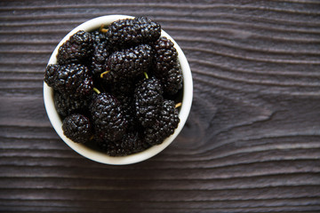 fresh mulberry in bowl on wooden background