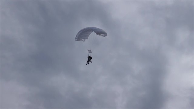 Parachutist landing with white emergency parachute . Plane landing in the background.