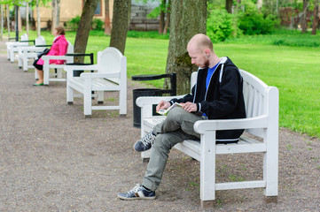 Young man reads on a bench in park