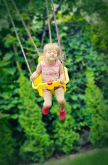 Cute little girl swings. Outdoors scenery.