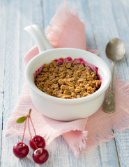 Homemade cherry crumble on a blue toned wooden background