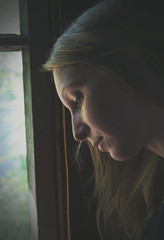 Fototapeta na wymiar Pensive girl near window.
