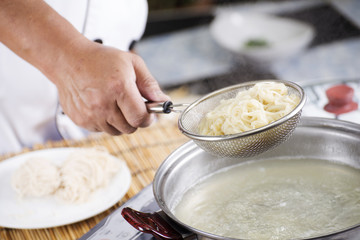 Chef holding colander with cooked Noodle