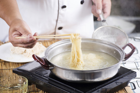 Chef holding the noodle from the pot with chopsticks