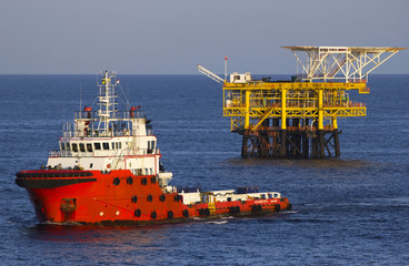 Oil platform and a supply vessel at sunset