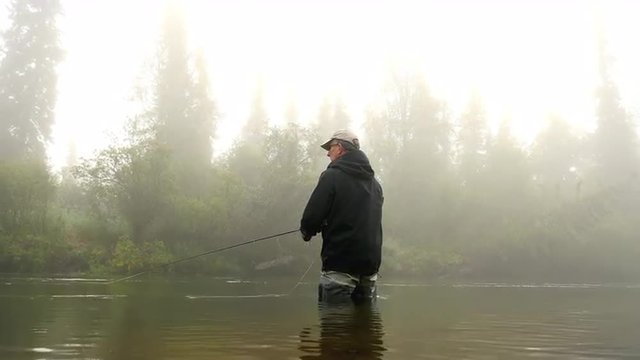 Man Fly-Fishing in a River Enveloped by Fog