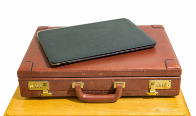 close black laptop and old vintage brown briefcase on wood table isolated